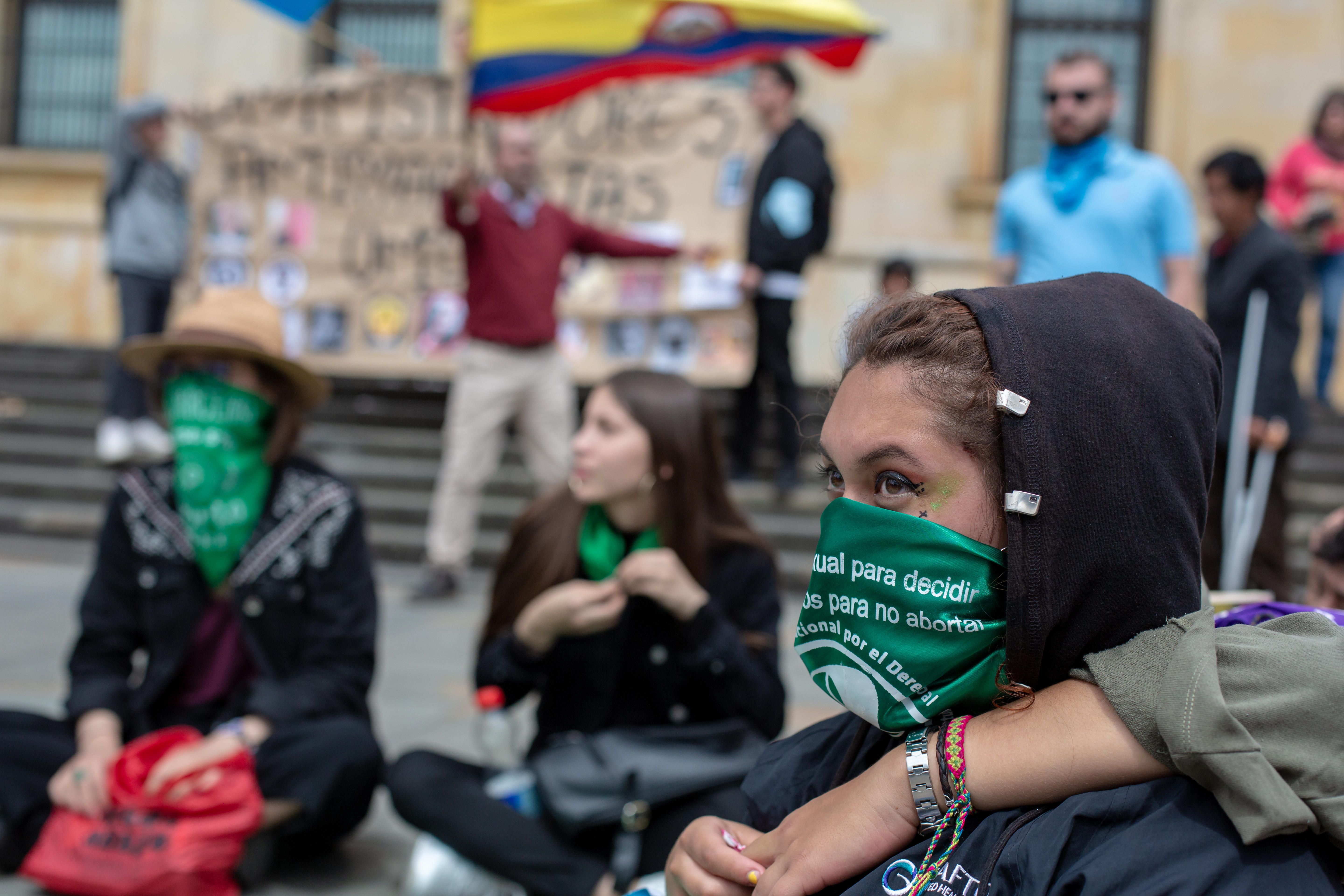 Abortion rights protestor with green scarf over her face