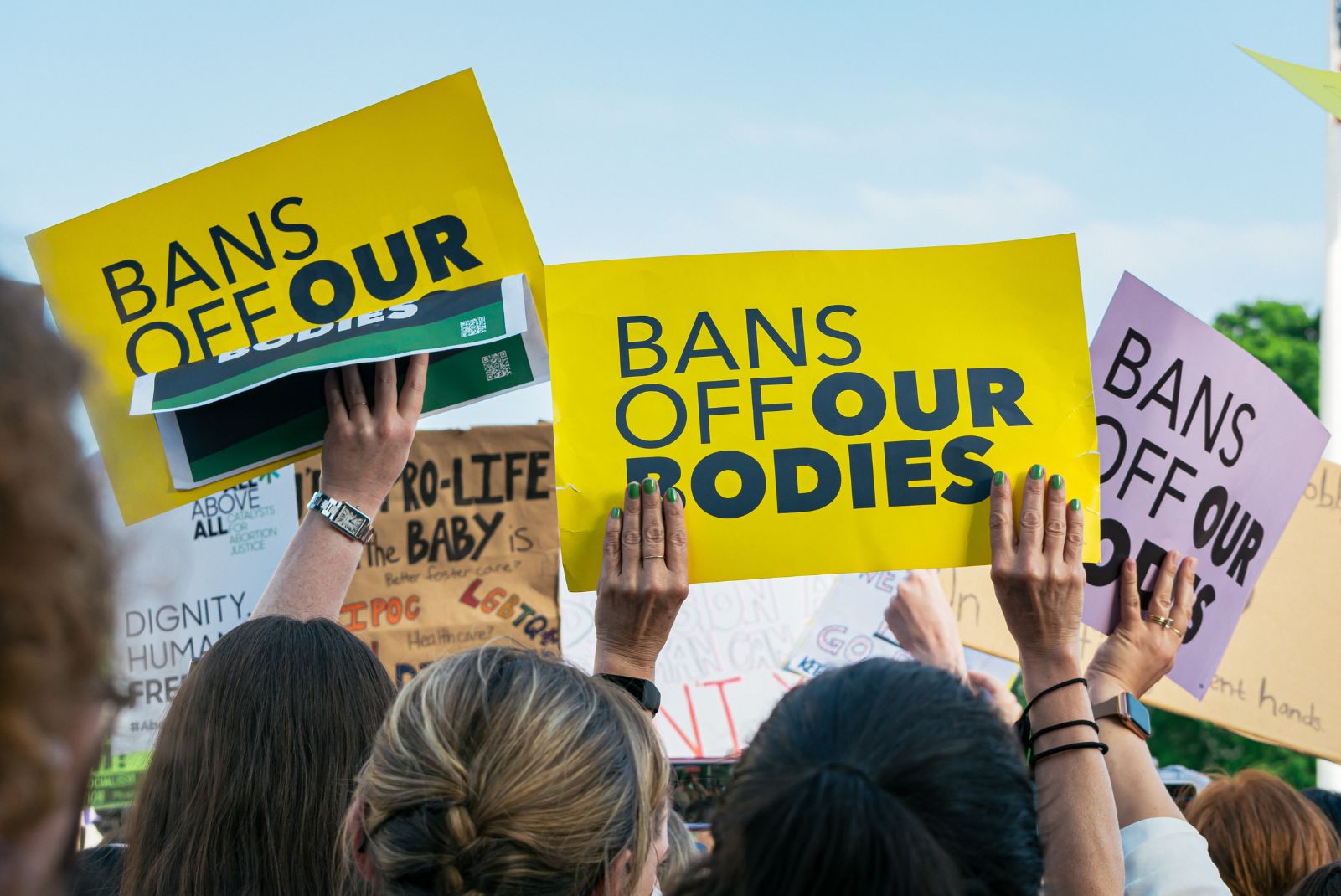 women holding signs saying bans off our bodies