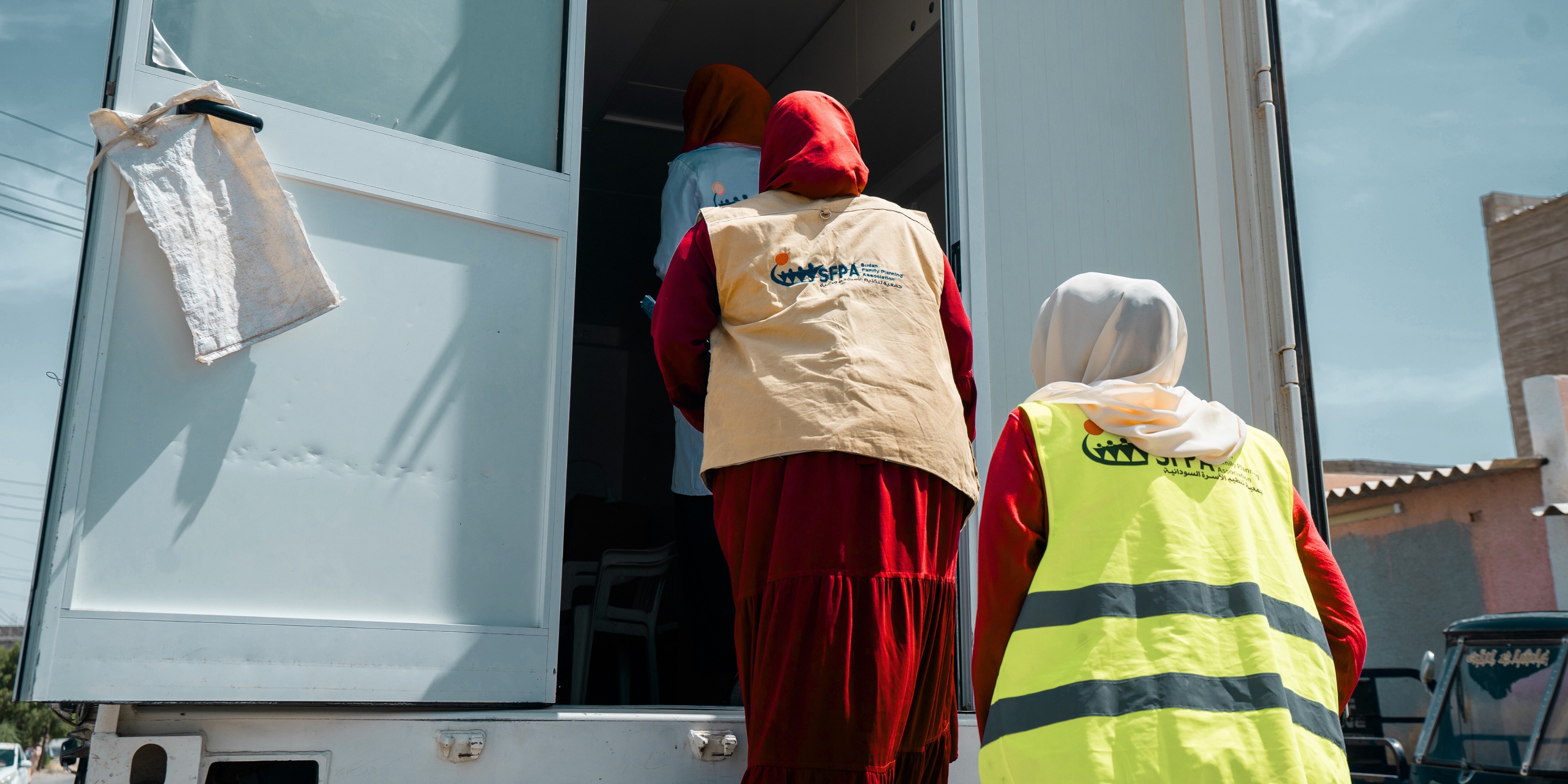 Two women load medical items into the back of a blue truck in Sudan. 