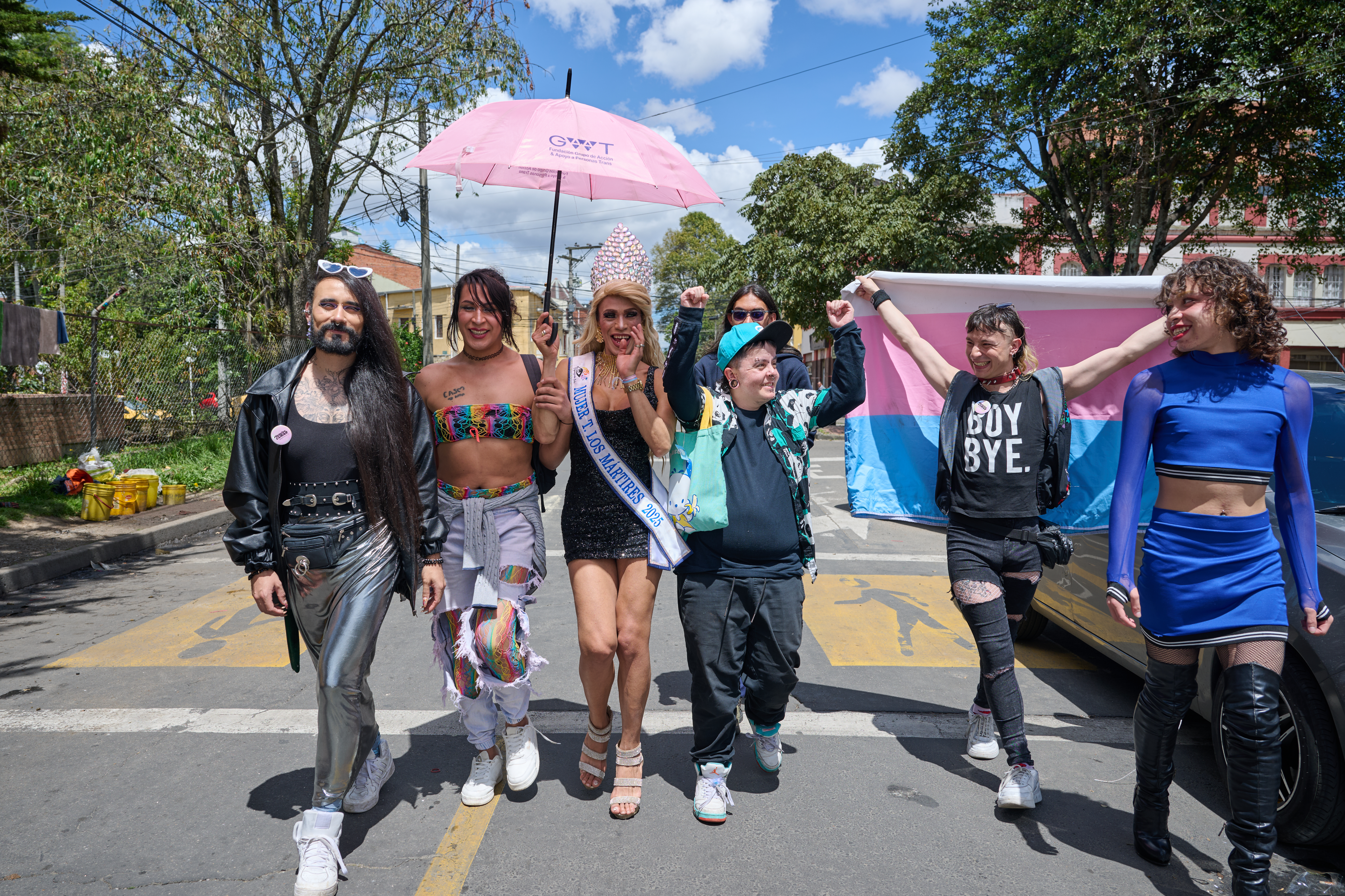 Members of the LGBTQI+ community walk towards the camera in Colombia. They are happy and holding their hands in the air. 