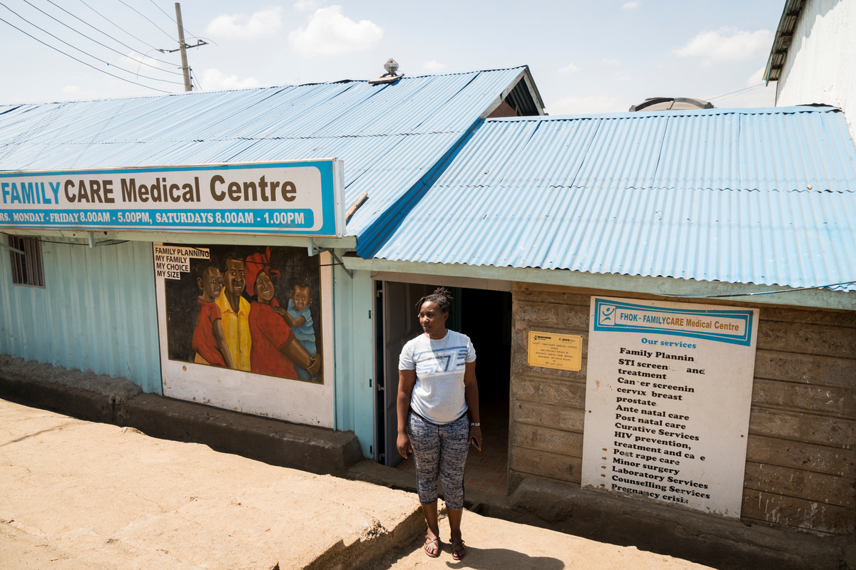 Community Health Volunteer Mary Mukuni, stands for a portrait outside of the Family Care Medical Centre (FHOK) in Kibera, Nairobi, Kenya
