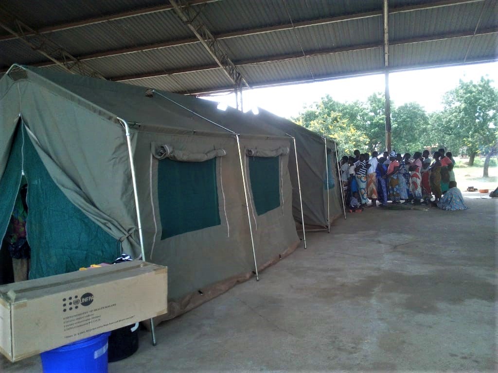 Clients queuing up for SRH Services at Bangula Evacuation Camp. Inside the shelter are FPAM tents.