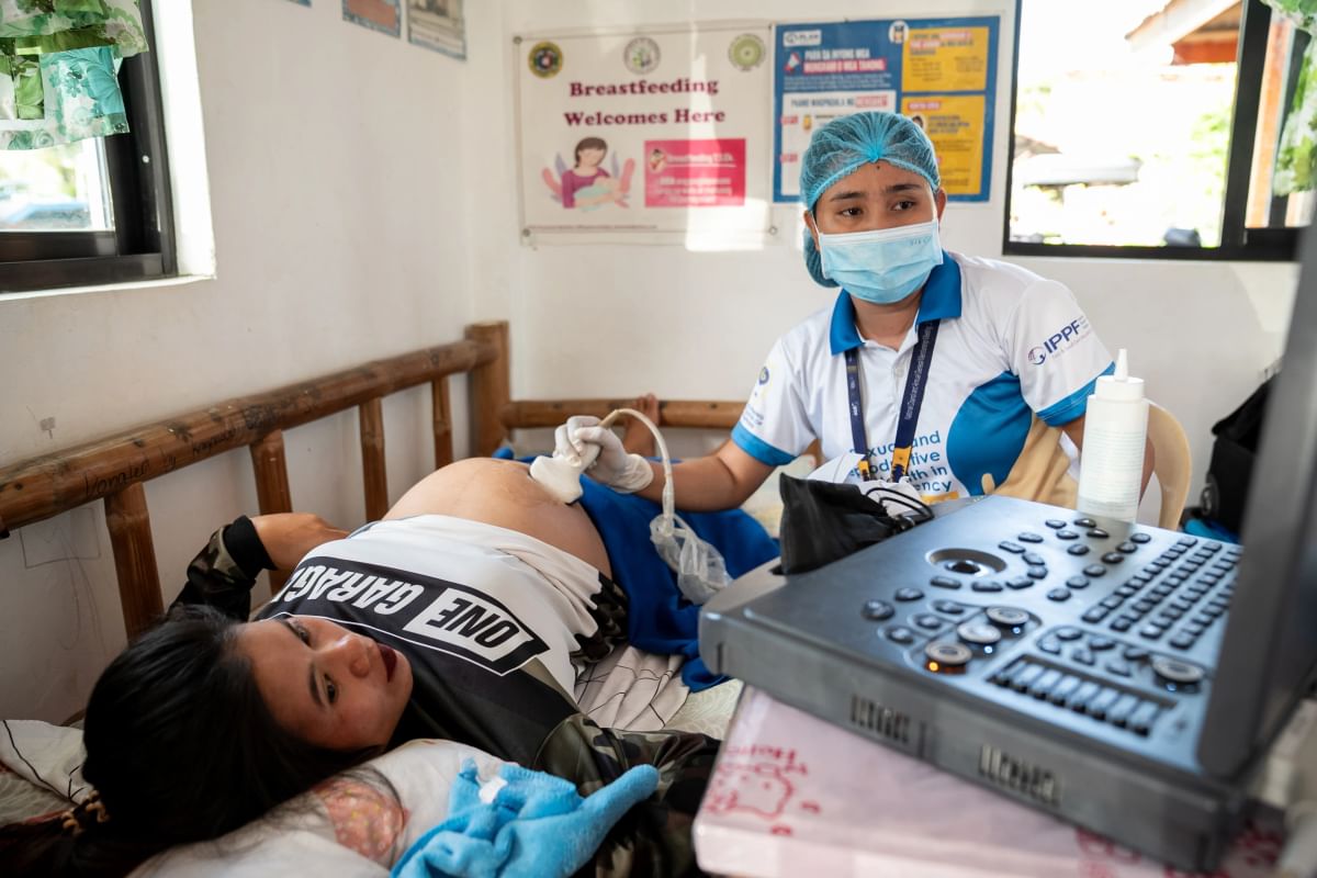 A healthcare worker performs an ultrasound on a pregnant woman in the aftermath of a typhoon in the Philippines