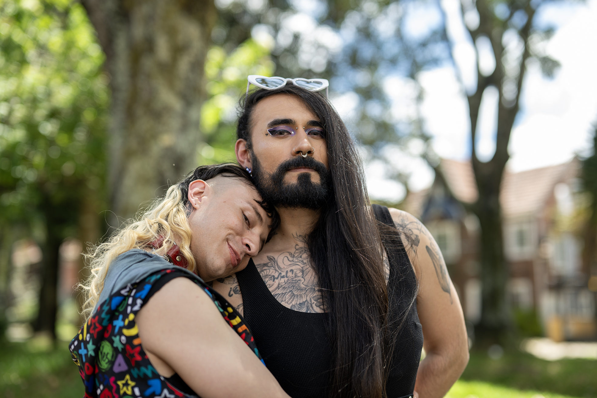 Danne looks directly at the camera being hugged by another member of the trans community