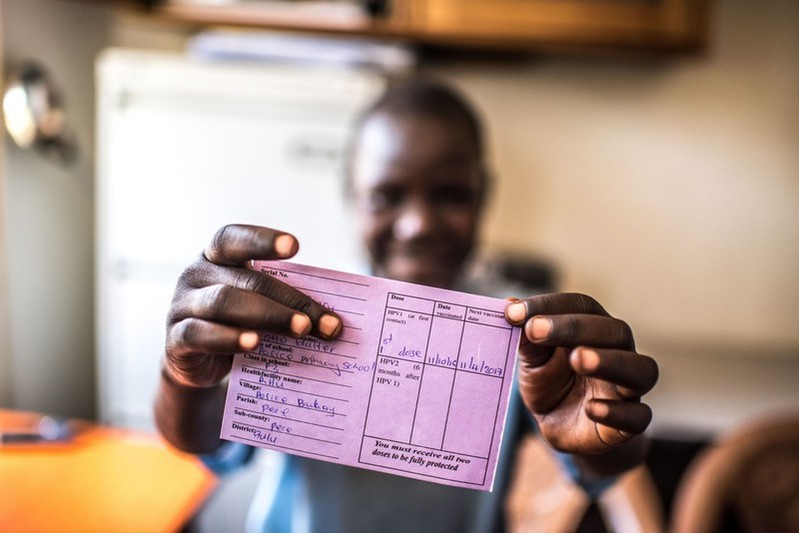 Aciro proudly displays her HPV vaccination card at the RHU clinic in Gulu in Uganda.