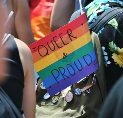 Rainbow flag which reads "queer & proud"
