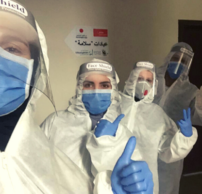 Healthcare workers in PPE giving a thumbs up