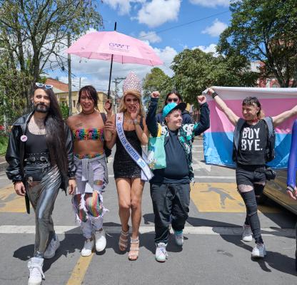 Members of the LGBTQI+ community walk towards the camera in Colombia. They are happy and holding their hands in the air. 
