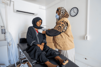 A female healthcare professional examines a woman at a clinic in Sudan