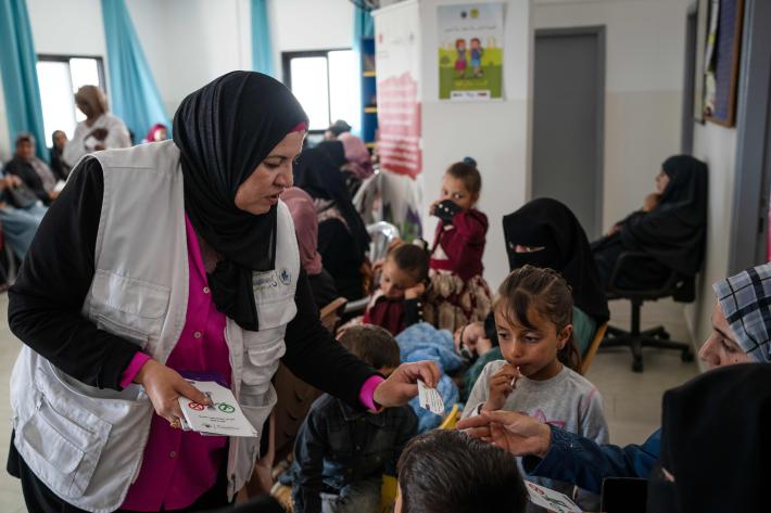 A healthcare hands out leaflets to mothers in a mobile clinic.
