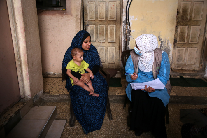 A health care professional speaks with a mother holding a baby. 