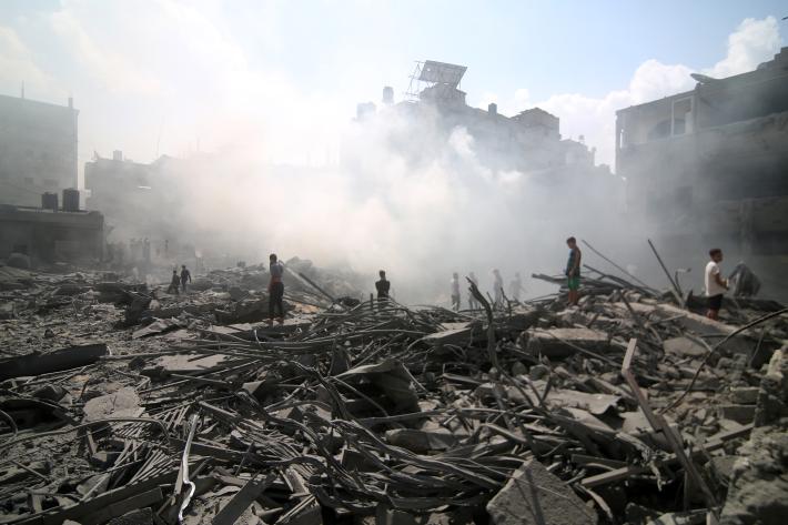People stand on the rubble of a bombed building in Palestine