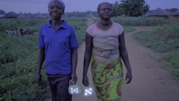 Two Ghanaian women carry torches in the dark