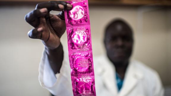 A health practitioner holds up condoms in Gulu clinic, Uganda