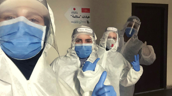 Healthcare workers in PPE giving a thumbs up