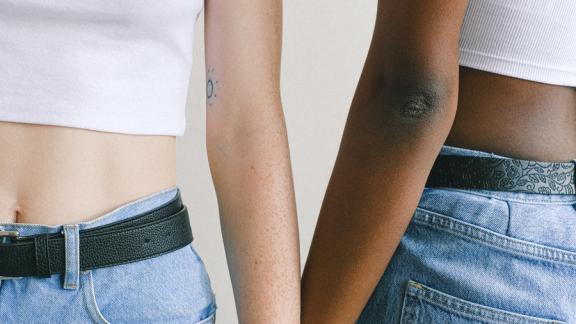 Two women holding hands, one with a Pride flag painted on