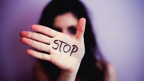 A woman with her hand in front of her face. Written on her hand is "STOP"