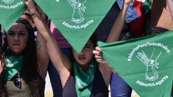 Woman waving a green flag in support of abortion care 