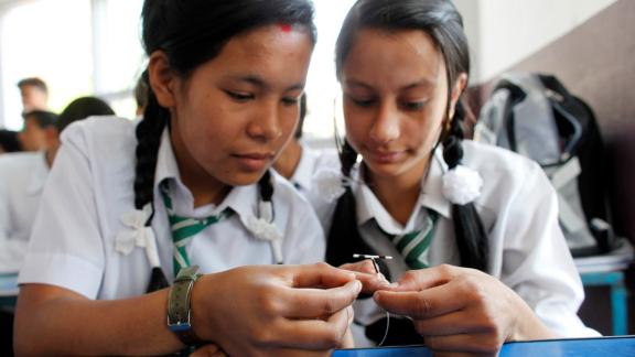 Two young people holding an IUD