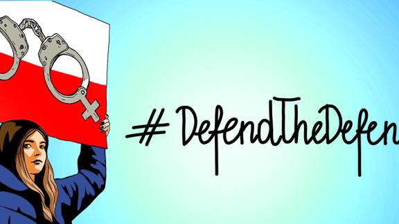 woman holding a sign saying defend the defenders 