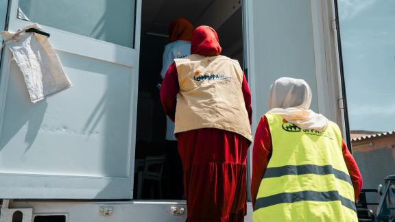 Two women load medical items into the back of a blue truck in Sudan. 