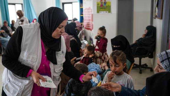 A healthcare hands out leaflets to mothers in a mobile clinic.