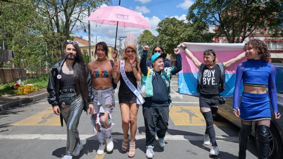 Members of the LGBTQI+ community walk towards the camera in Colombia. They are happy and holding their hands in the air. 