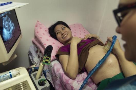 Nurse with mother conducting ultrasound, Philippines